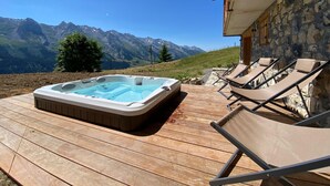 Un bain à remous sur une terrasse en bois avec vue sur les montagnes.