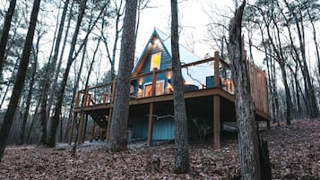 Situated in a forested area, this cabin offers a view of the surrounding trees from its elevated position.
