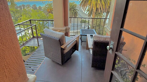 A balcony with outdoor furniture, a view of the ocean, and a palm tree. - Penthouse with Unobstructed Views! (San Pedro)