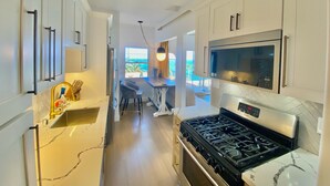 A modern kitchen with white cabinetry, a stainless steel stove, and a large window overlooking a scenic view. - Penthouse with Unobstructed Views! (San Pedro)
