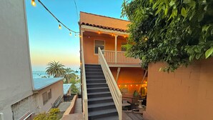 A staircase leading to a balcony with a view of the sea, a doormat with "oh hello" written on it, and string lights. - Penthouse with Unobstructed Views! (San Pedro)