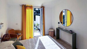 Een hotelkamer met een bed, een stoel, een tafeltje, een spiegel en uitzicht op het omliggende landschap.