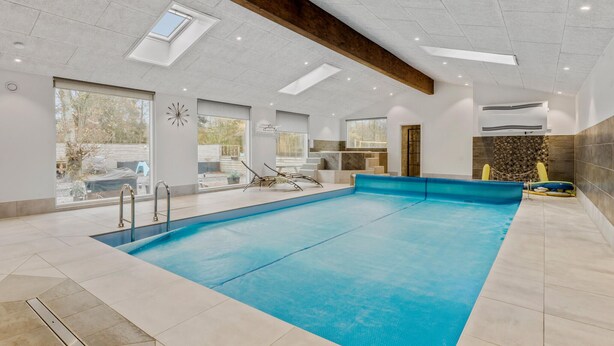 Ein geräumiger, überdachter Pool mit freiem Blick ins Freie, großen Fenstern und einem modernen Design inklusive Oberlichter.
