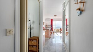 Ein Flur, der zu einem Balkon mit Blick führt, eine hölzerne Kommode und ein roter Vorhang.