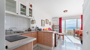 Eine moderne Küche mit Kochinsel, ein Essbereich mit Aussicht und ein Balkon mit Tisch und Stühlen.