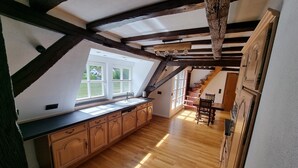 A kitchen with wooden cabinets, a large window, and a staircase leading to an upper level.