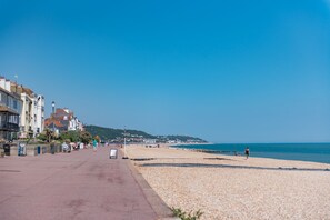 Une promenade en bord de mer, bordée d’immeubles d’un côté et d’une plage de galets de l’autre.