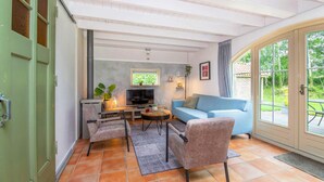 A cozy living room with a sofa, two chairs, a TV, and a small table with a plant.