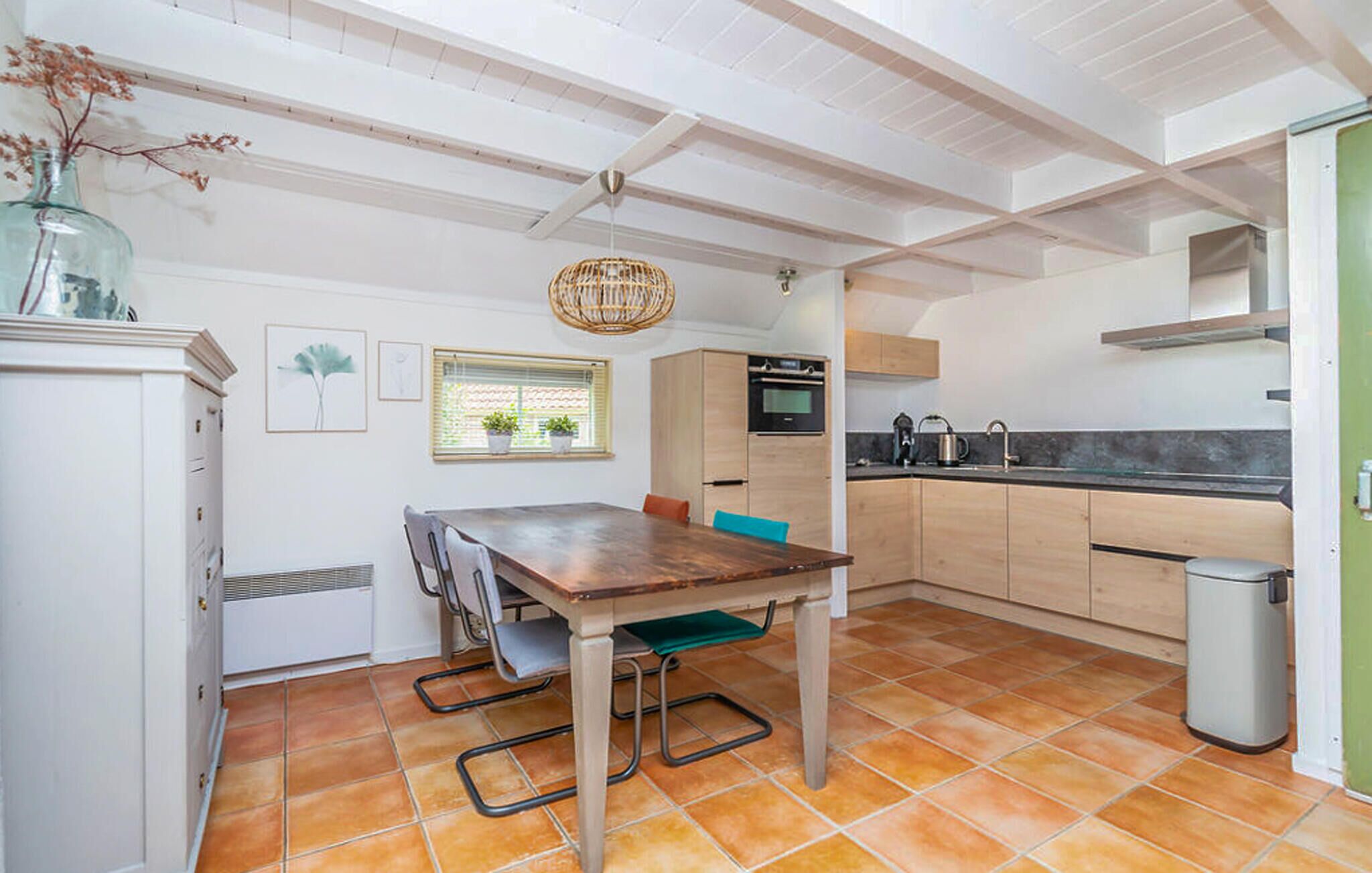 Une cuisine compacte comprenant une table à manger, un four encastré et un évier.