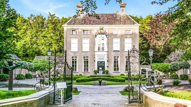 A historic building with a symmetrical facade, a central entrance, and a well-maintained garden.