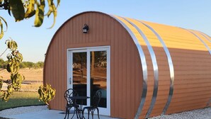 A small, single-story building with a curved roof and a large sliding glass door. - Cabernet Cabin (Seguin)