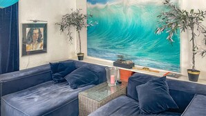 Un salon avec des canapés bleu foncé, une table basse en verre et deux plantes en pot.