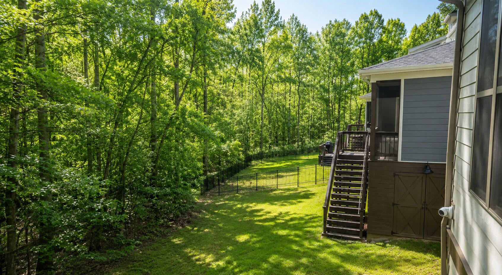 A residential property with a fenced yard, a wooden deck, and a garage.