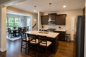 A modern kitchen with dark wooden cabinets, stainless steel appliances, and a central island with bar stools.