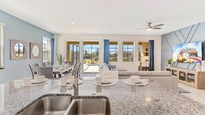 A modern kitchen with granite countertops, stainless steel sinks, and a dining area with a table and chairs. - 7663 Oakmoss Loop (Davenport)