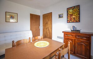 Ein Essbereich mit Holztisch, Stühlen, einer Couch und einem Schrank mit Büchern.
