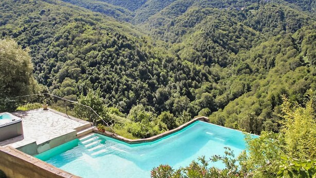 Piscina com vista para colinas arborizadas.