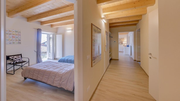 Ein Schlafzimmer mit Bett, Stuhl, Kalender und einer Tür, die auf einen Balkon führt.