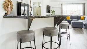 A modern kitchen with a central island, bar stools, and a ceiling fan. - NEW - Lauhala - Hawaiian Villa with private hot tub (Keaau)