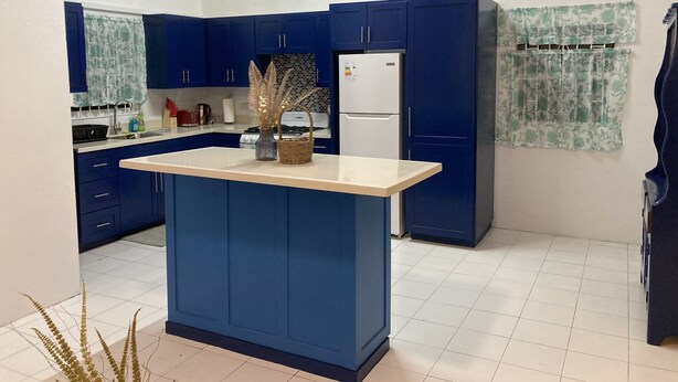 Una cocina con armarios azules, un refrigerador blanco y una isla central.