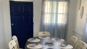 Un comedor con una mesa redonda, seis sillas y una puerta azul.