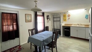 A dining area with a table, chairs, a ceiling fan, and a kitchen area with cabinets and a sink. - Secluded Luxury Escape Near Katahdin & Acadia (Greenbush)