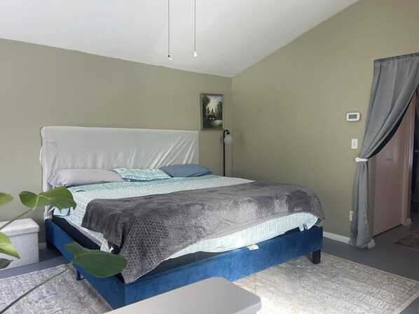Ein Schlafzimmer mit Bett, Nachttisch und Topfpflanze.