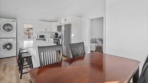 A modern kitchen with a central island, built-in appliances, and a dining area with a wooden table and chairs. - Newly Renovated Beach House w/ Central AC - 5min walk to the beach (Dennis)