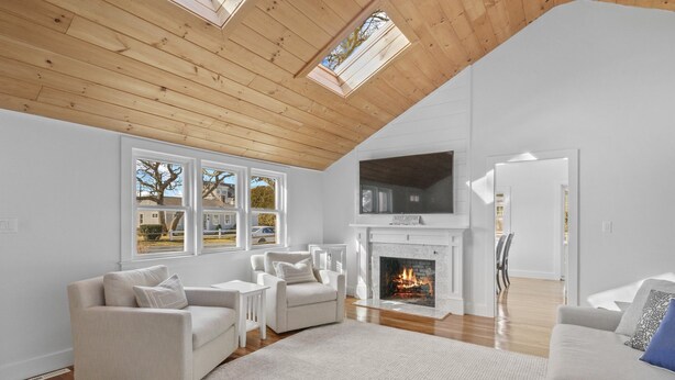 A spacious living room with a high ceiling, a fireplace, and a large TV. - Newly Renovated Beach House w/ Central AC - 5min walk to the beach (Dennis)