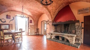 Un'ampia stanza con camino in mattoni, un tavolo da pranzo con sedie e un lampadario.
