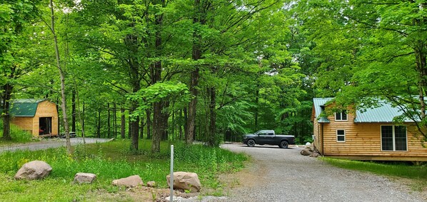 A cabin area with two wooden cabins, a gravel path, and a parked truck.