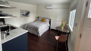 A compact bedroom with a bed, bedside table, and a small dining area with a chair. - Bachelor Suite Bed & Breakfast in Northern Muskoka (Huntsville)