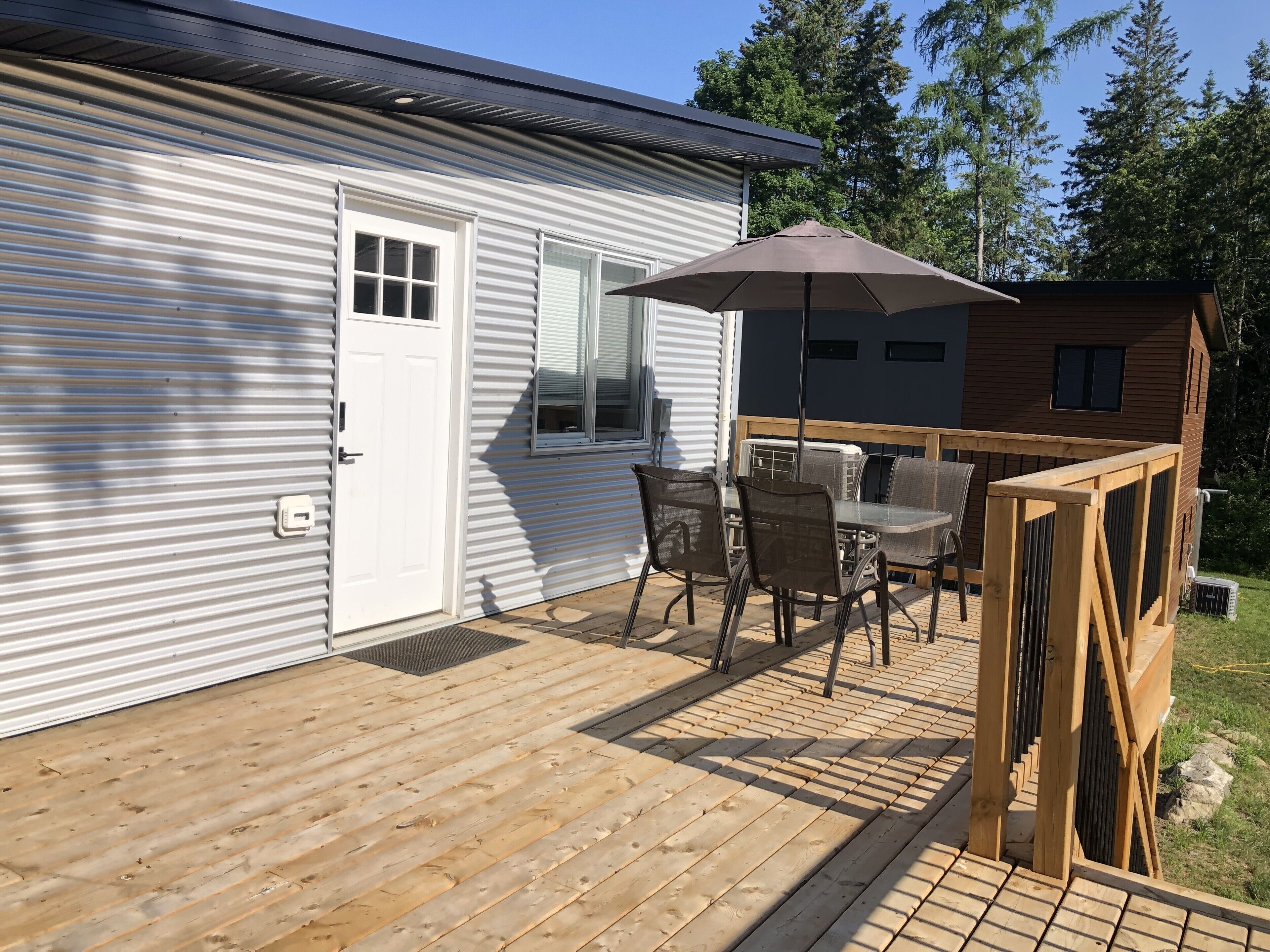 En træterrasse med et bord og stole, en overdækket patio og en lille træbygning.