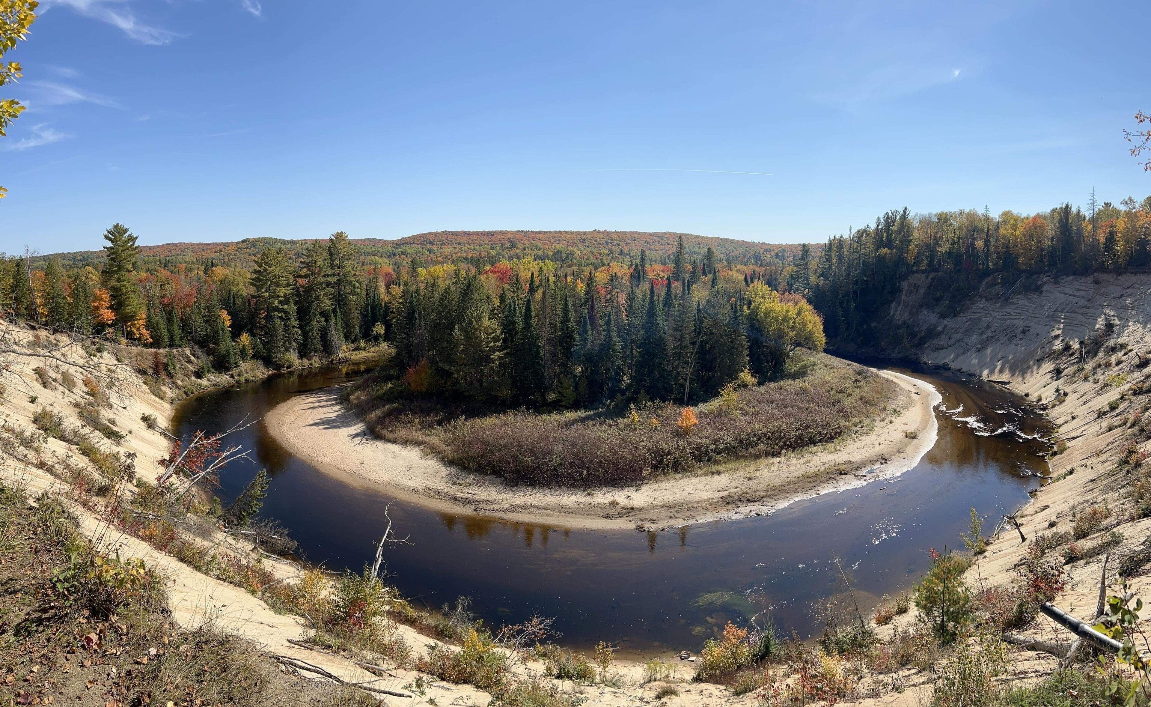 A natural landscape with a river, forest, and hills.
