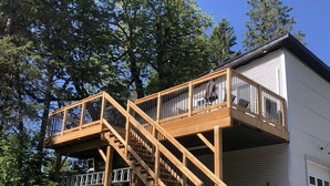 A two-story wooden deck with a staircase leading to a garage. - Bachelor Suite Bed & Breakfast in Northern Muskoka (Huntsville)