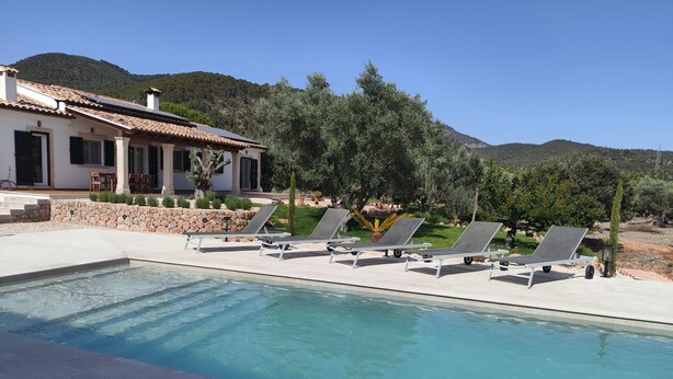 A pool with lounge chairs, a stone wall, and a house with a tiled roof. - 4 bedroom country house with pool and barbecue (Bunyola)
