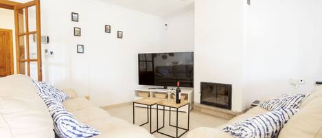 A living room with two beige sofas, a wooden coffee table, a flat-screen TV, and a fireplace.
