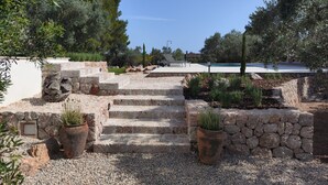 A stone staircase leading to a pool area, surrounded by olive trees and potted plants. - 4 bedroom country house with pool and barbecue (Bunyola)