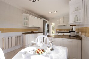 A modern kitchen with white cabinetry, a granite countertop, and a dining area with a white table set for two. - 4 bedroom country house with pool and barbecue (Bunyola)