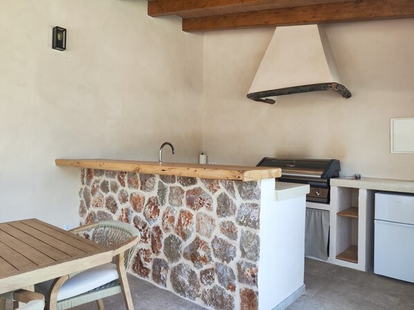 A kitchen with a stone wall, wooden countertop, and a grill. - 4 bedroom country house with pool and barbecue (Bunyola)