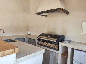 Una cocina compacta con estufa a gas integrada, un lavamanos y una encimera de madera.