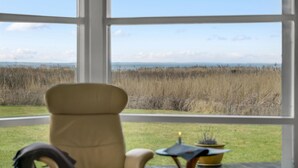 Ein Zimmer mit großem Fenster und Blick auf eine Rasenfläche sowie ein Gewässer.