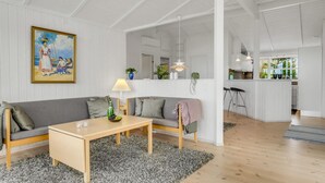 Ein geräumiger Wohnbereich mit einer Couch, einem Couchtisch und einem Gemälde an der Wand.