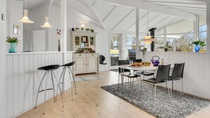 Eine moderne Küche mit weißen Schränken, einem Essbereich mit rundem Tisch und schwarzen Stühlen sowie Pendelleuchten.