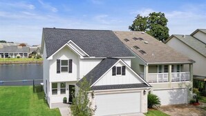 A two-story house with a garage, a covered porch, and a small yard. - New Waterfront House with Golf Cart!  (Montgomery)
