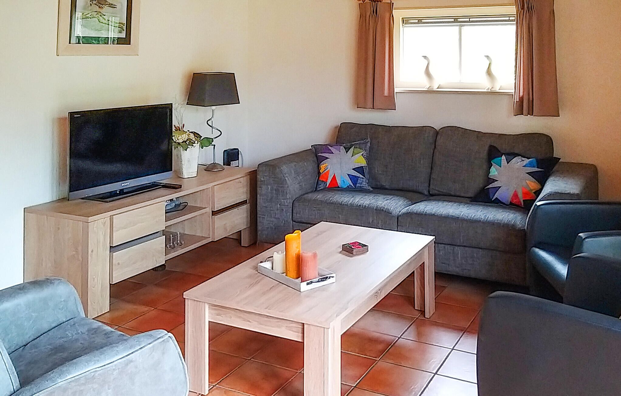 A living room with a sofa, a coffee table, a TV, and a lamp.