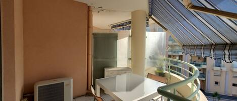 A balcony with a table and chairs, a radiator, and a view of neighboring buildings.