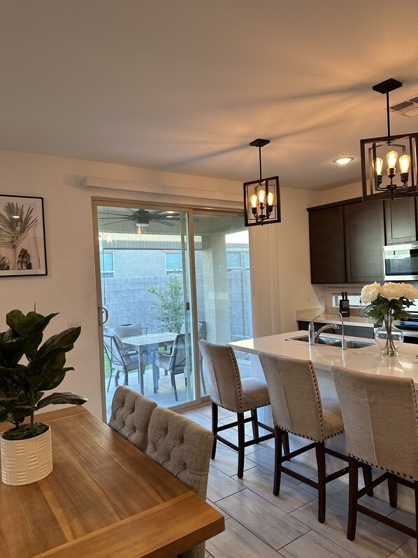 Una cocina moderna con comedor, que incluye una mesa de madera, sillas y un amplio ventanal con vistas a un patio.