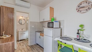 A compact kitchen with a microwave, a small refrigerator, a sink, and a dining area with a table and chairs. - Gorgeous home in Potomje with WiFi (Potomje)