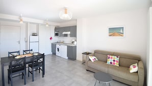 Un appartement moderne comprenant un coin repas, une kitchenette et un salon avec un canapé et des coussins.